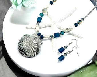 May include: A silver seashell pendant necklace with blue and white glass beads. Matching earrings with blue glass beads.