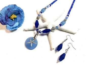 May include: A blue glass necklace with a starfish pendant and matching earrings. The necklace features blue and clear glass beads and silver accents. The earrings are dangle style with a blue glass bead and silver accents.