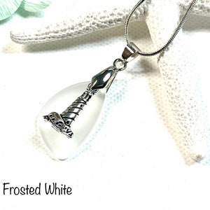 May include: A frosted white glass teardrop pendant with a silver lighthouse charm. The pendant is on a silver chain.