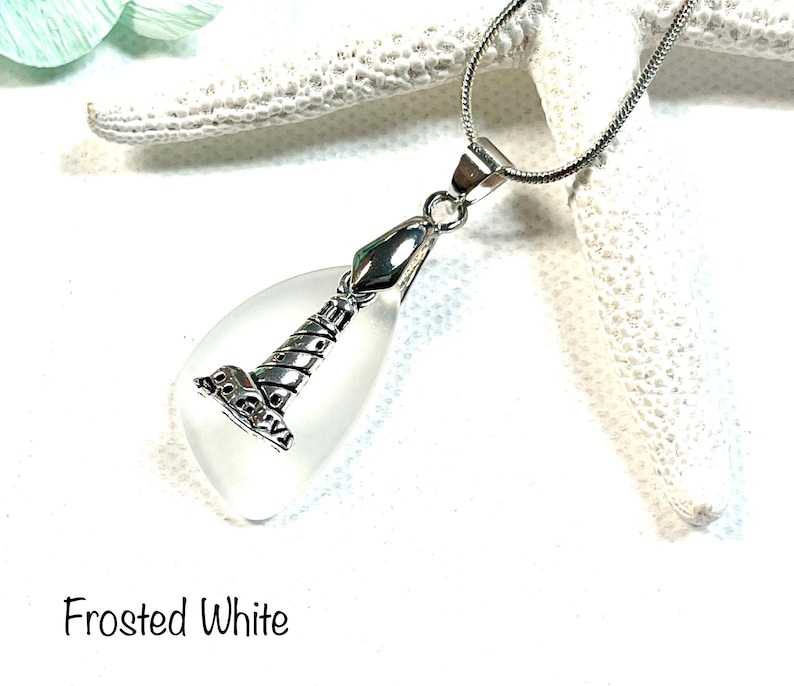 May include: A frosted white glass teardrop pendant with a silver lighthouse charm. The pendant is on a silver chain.