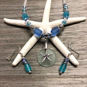 May include: A sea glass necklace and earrings set with a starfish pendant. The necklace features blue and clear glass beads with silver accents. The earrings are silver with blue glass beads.