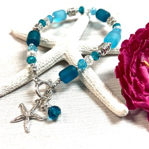 May include: A blue and silver beaded bracelet with a starfish charm. The bracelet is made with glass beads and silver beads. The starfish charm is attached to a silver clasp.
