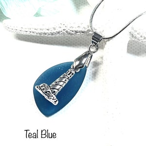 May include: Teal blue sea glass pendant necklace with a silver lighthouse charm.  The necklace is on a silver chain.