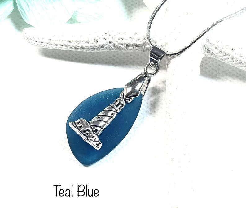 May include: Teal blue sea glass pendant necklace with a silver lighthouse charm.  The necklace is on a silver chain.