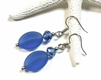 May include: A pair of blue glass and crystal earrings with silver hooks. The glass beads are oval shaped and the crystal beads are faceted.