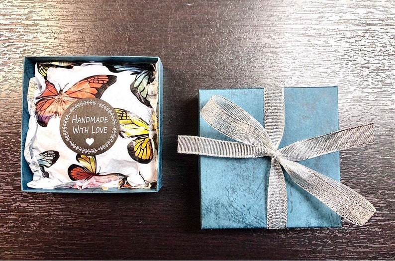 May include: A small blue gift box with a silver ribbon and a white box with a butterfly pattern inside. The white box has a sticker that says "Handmade with Love".