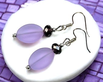 May include: A pair of dangle earrings with a light purple oval bead and a dark purple crystal bead on each earring.