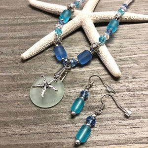 May include: A sea-themed jewelry set with a necklace and earrings. The necklace features a light blue glass pendant with a silver starfish charm. The earrings are silver with light blue glass beads.