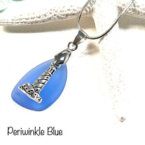 May include: A silver lighthouse charm pendant on a silver chain, hanging from a light blue sea glass teardrop.
