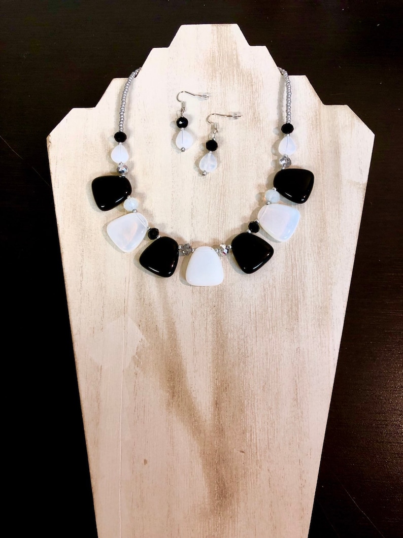 May include: A black and white statement necklace with matching earrings. The necklace features large, irregular shaped black and white beads.