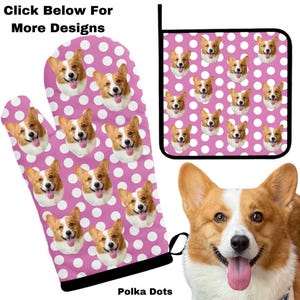May include: A pink oven mitt and matching pot holder with a white polka dot pattern. The pattern features a repeated image of a corgi dog's face. The text "Polka Dots" is printed below the oven mitt.