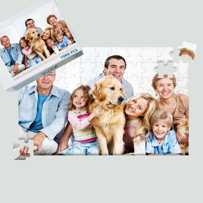 Puede incluir: Un rompecabezas de un retrato familiar con un perro golden retriever. El rompecabezas est&aacute; parcialmente montado, con la caja que muestra la imagen completa. La caja dice "1000 PCS". La imagen muestra un grupo de personas sonriendo.