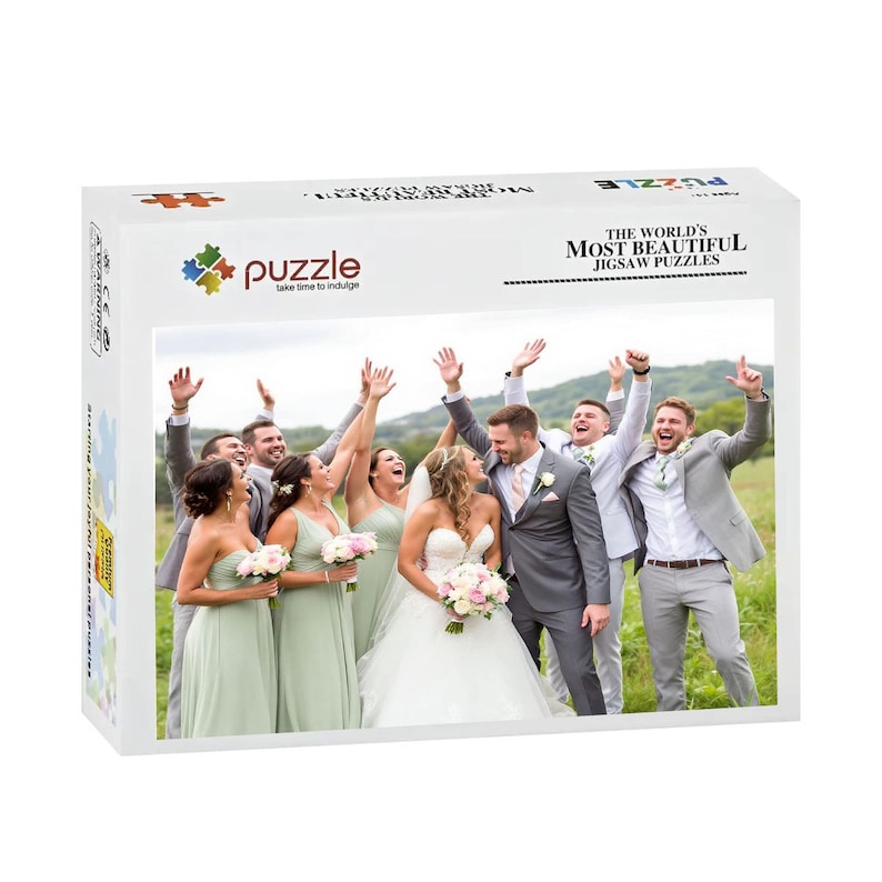 Puede incluir: Una caja de rompecabezas blanca con una foto de boda de una novia y un novio con su cortejo. La caja tiene el texto "The World's Most Beautiful Jigsaw Puzzles" y el nombre de la marca "puzzle".