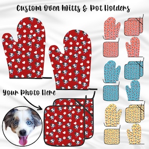 May include: Custom oven mitts and pot holders with a red background and a pattern of white hearts and paw prints. The pattern also includes a repeated image of a dog's face. The text "your photo here" is written on the image.