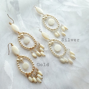 May include: Two pairs of chandelier earrings. One pair has gold-colored hooks and accents, the other has silver-colored hooks and accents. Both pairs feature oval and round white shell pieces, faux pearls, and dangling shell-shaped beads. The word "Gold" and "Silver" are written on the image.
