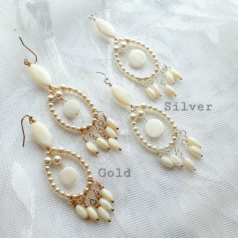 May include: Two pairs of chandelier earrings. One pair has gold-colored hooks and accents, the other has silver-colored hooks and accents. Both pairs feature oval and round white shell pieces, faux pearls, and dangling shell-shaped beads. The word "Gold" and "Silver" are written on the image.