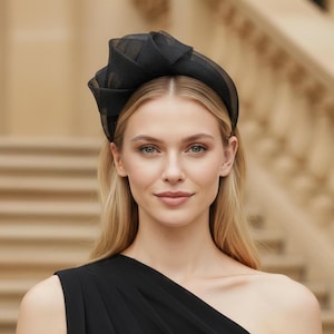 Peut inclure: Un serre-tête noir doté d'un accent en tissu maillé structuré et superposé sur un côté. L'accessoire est porté sur la tête, présentant un design de bande large et lisse qui repose solidement sur le dessus, fabriqué dans une matière sombre et semi-transparente.