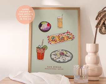 May include: A framed art print on a light green background featuring illustrations of a smoothie bowl, an iced coffee, three tacos on a red and white checkered paper, a red cocktail with a lime slice, and a plate of oysters with the text SAN DIEGO.