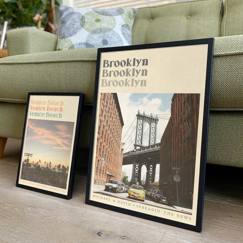 Puede incluir: Dos impresiones enmarcadas con dise&ntilde;os de estilo vintage. La impresi&oacute;n de la izquierda presenta una puesta de sol sobre una playa bordeada de palmeras con el texto "Venice Beach" repetido tres veces. La impresi&oacute;n de la derecha presenta una vista del puente de Brooklyn con el texto "Brooklyn" repetido tres veces. El texto "MICHAEL & DAVID SPREADIN' THE NEWS" est&aacute; en la parte inferior de la impresi&oacute;n.