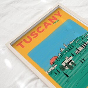 K&ouml;nnte beinhalten: Eine gelbe, blaue und gr&uuml;ne Illustration einer toskanischen Landschaft mit einer roten Sonne, die hinter einem Bergdorf untergeht. Der Text "Tuscany ITALY" steht in roten Buchstaben auf gelbem Hintergrund.