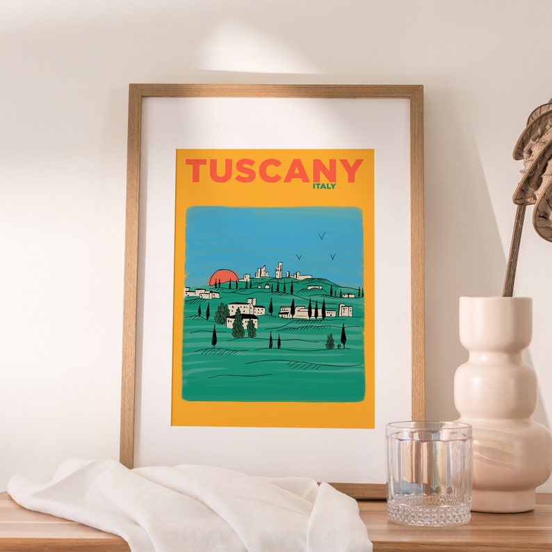 K&ouml;nnte beinhalten: Ein gelber und gr&uuml;ner illustrierter Poster mit dem Text "Tuscany, Italy" oben. Der Poster zeigt eine stilisierte Landschaft mit sanften H&uuml;geln, einer kleinen Stadt und einer untergehenden roten Sonne in der Ferne.