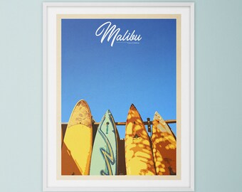 May include: A vintage-style poster with the text "Malibu, California" in a white frame. The poster features a colorful illustration of five surfboards hanging on a rack against a blue sky.