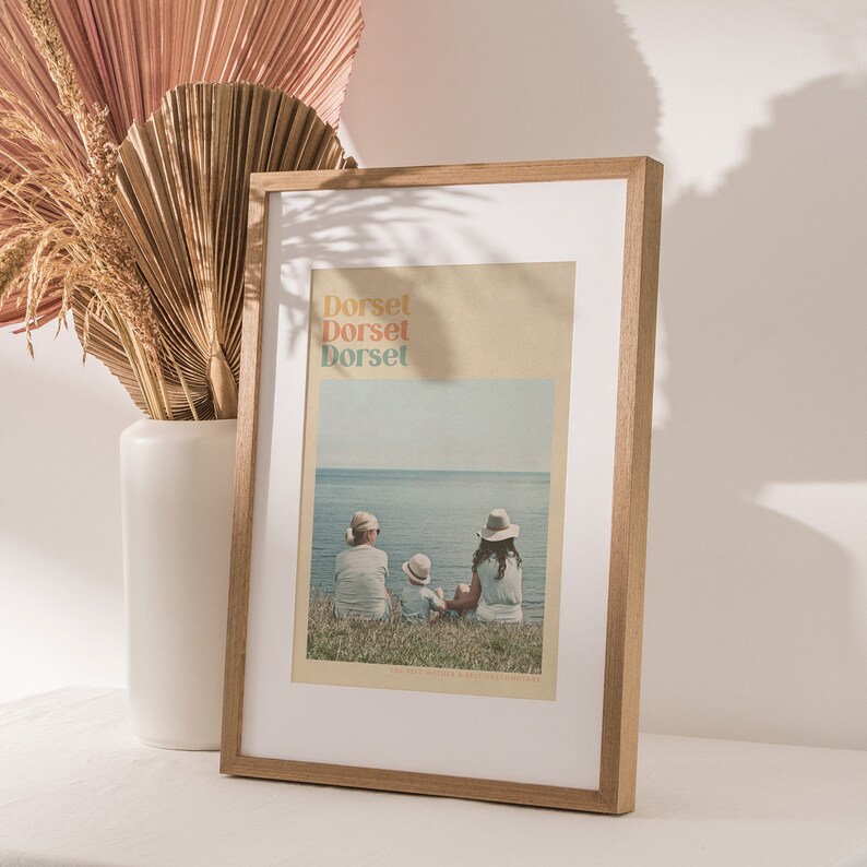 Puede incluir: Una impresi&oacute;n enmarcada con una foto de tres personas sentadas en una playa. La foto est&aacute; en un marco marr&oacute;n claro. El texto "Dorset" se repite tres veces en diferentes colores en la impresi&oacute;n.