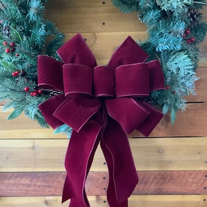 May include: A deep red velvet bow with long tails, perfect for adding a touch of elegance to a Christmas wreath.