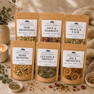 May include: Six brown kraft paper pouches of stovetop simmer kits labeled New Beginnings, Love & Harmony, Peace & Calm, Home Blessing, Cleanse & Protect, and Joy & Abundance. Each pouch contains dried botanical ingredients visible through a clear window.
