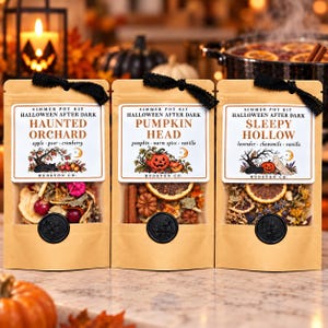 May include: Three tan paper pouches of simmer pot kits labeled Halloween After Dark. The labels read Haunted Orchard, Pumpkin Head, and Sleepy Hollow, featuring dried fruits, spices, and botanicals visible through clear windows with black wax seals.