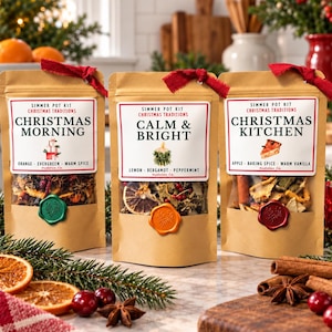 May include: Three brown paper pouches labeled Simmer Pot Kit Christmas Traditions. The labels read Christmas Morning, Calm & Bright, and Christmas Kitchen, featuring dried fruit, spices, and wax seals in green, orange, and red.