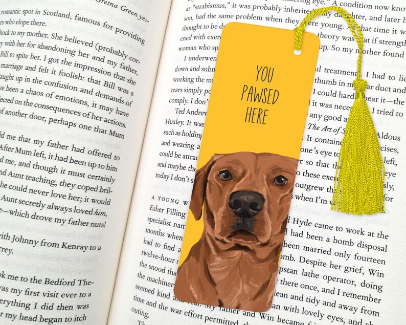 May include: Yellow bookmark with a brown dog illustration and the text "You Pawsed Here". The bookmark has a yellow tassel.
