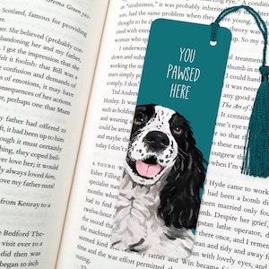 May include: Teal blue bookmark with a black and white illustration of a dog with the text "You Pawsed Here".