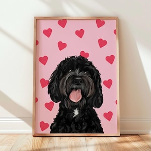 May include: A framed print of a black dog with a pink tongue, set against a pink background with red heart shapes. The dog has a white patch on its chest. The frame is made of light brown wood.