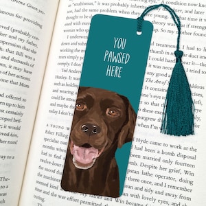 Könnte beinhalten: Türkisblaues Lesezeichen mit einer Illustration eines braunen Labrador Retrievers. Das Lesezeichen trägt den Text "You Pawsed Here" in Weiß.