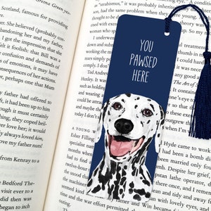 May include: A blue bookmark featuring a white dalmatian dog illustration. The bookmark has the text "You Pawsed Here" in white lettering.