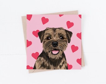 May include: Greeting card featuring a smiling dog with brown and black fur, set against a pink background with red hearts. The card is on a neutral-toned envelope, perfect for sending a message of love.