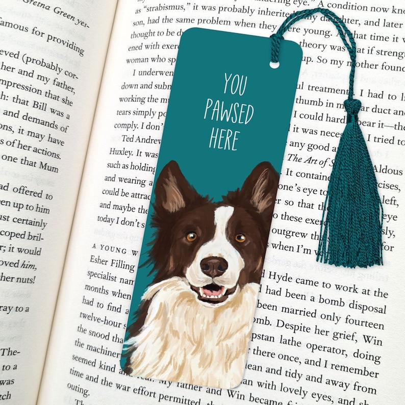 Pode incluir: Marca-p&aacute;ginas azul turquesa com uma ilustra&ccedil;&atilde;o pintada &agrave; m&atilde;o de um border collie castanho e branco. O marca-p&aacute;ginas tem o texto "You Pawsed Here" em letras brancas.