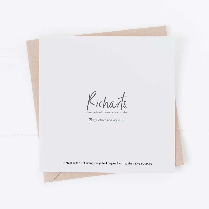 May include: A white card with the text "Richarts" in black script font. Below the text is the phrase "Guaranteed to make you smile" in smaller black font. Below that is a social media icon and the text "@richartsdesignsuk". At the bottom of the card is the text "Printed in the UK using recycled paper from sustainable sources".
