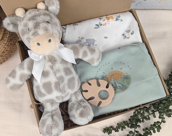 May include: A baby gift set in a cardboard box. The set includes a plush giraffe with a white bow, a light green onesie with the text "ADVENTURE WITH ME", a wooden teether, and a white blanket with animal illustrations.