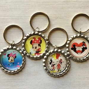 May include: Four silver bottle cap keychains with different Disney character designs. The keychains feature Mickey Mouse and Minnie Mouse in various poses, including a heart-shaped design with Mickey and Minnie kissing.