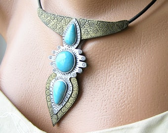 May include: A silver and gold necklace with a turquoise stone pendant. The necklace has a geometric design and is made of metal.