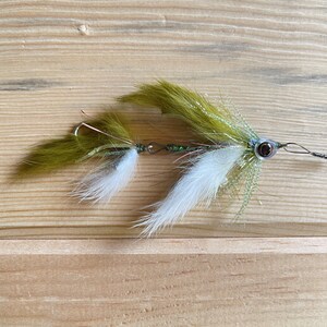 May include: A green and white fly fishing lure with a brown hook and a green and silver body.