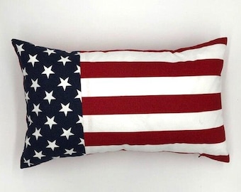 Könnte beinhalten: Rechteckiges Kissen mit dem Design der amerikanischen Flagge. Das Kissen hat einen marineblauen Bereich mit weißen Sternen und rot-weißen Streifen. Ein patriotischer Einrichtungsgegenstand, ca. 40 cm x 25 cm.