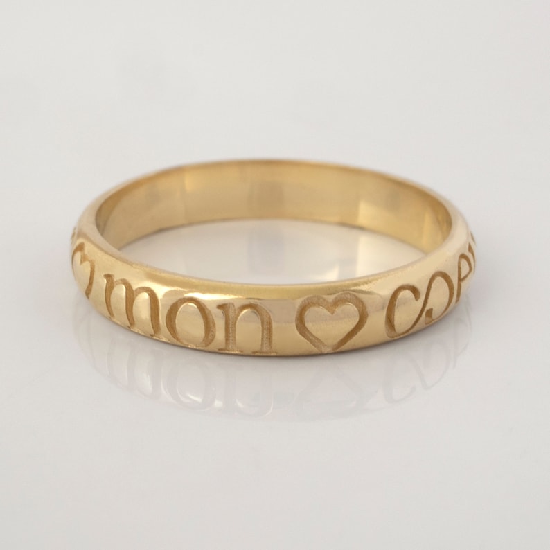 May include: A gold band ring with the inscription "mon coeur" and a heart symbol.