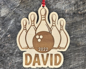 May include: Wooden Christmas ornament featuring a bowling ball and five bowling pins with the year 2022 and the name DAVID.