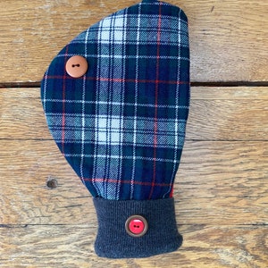 May include: A blue, green, red, and white plaid hand warmer with a gray cuff and two brown buttons. The hand warmer has a red button on the cuff.