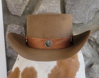May include: A brown felt cowboy hat with a brown leather band and a silver ace of spades design.