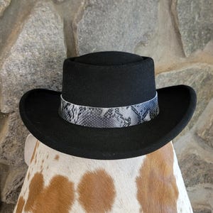 May include: A black felt fedora hat with a wide brim and a snakeskin patterned band.