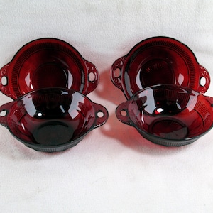 May include: Set of four red glass bowls with handles. The bowls are made of ruby red glass and have a fluted design.